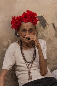 Une femme âgée avec des fleurs dans les cheveux fume un cigare