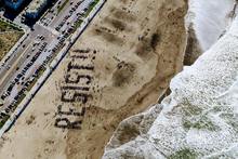 le mot résister est écrit sur la plage comem pour dire de ne pas prendre de bonnes résolutions